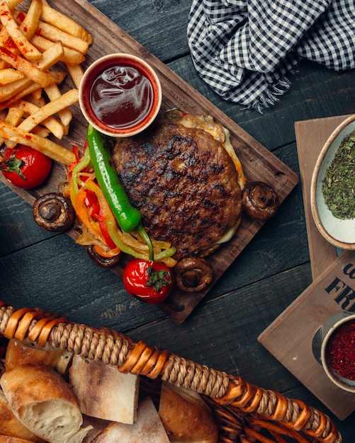 Hamburger senza agnello alla griglia servito con peperoni arrostiti, patatine fritte, funghi, ketchup