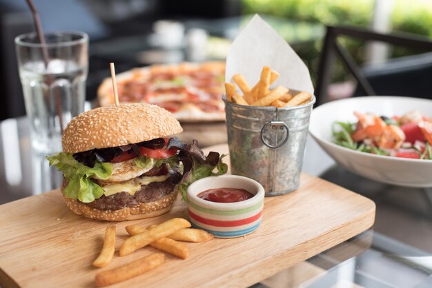 Hamburger su una tavola di legno con patate fritte