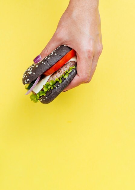 Hamburger tenuto di fronte a sfondo giallo