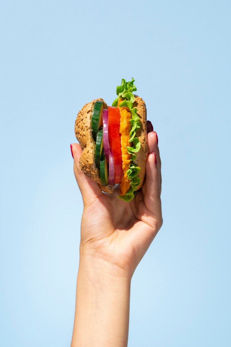 Foto gratuito hamburger vegetariano delizioso in una mano di persona