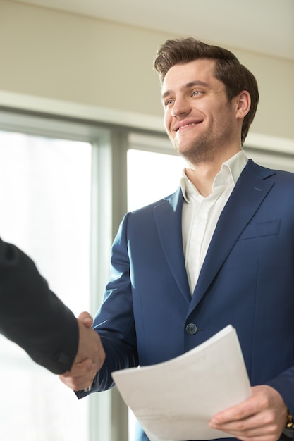 Handshaking sorridente del consulente finanziario con il cliente