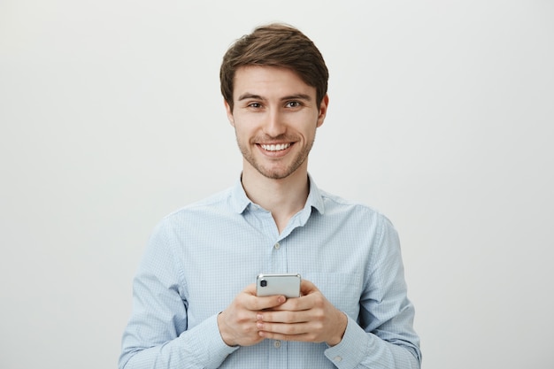 Handsome imprenditore utilizzando il telefono cellulare, sorridendo