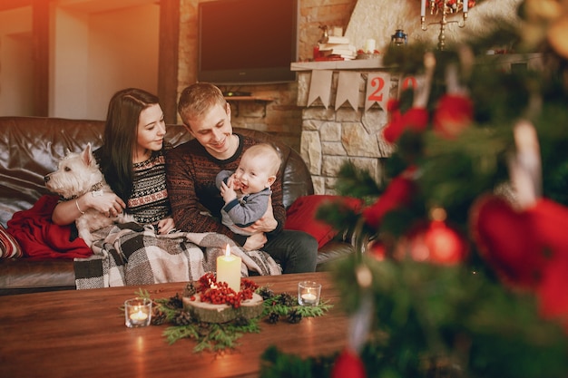 Happy Family seduto sul divano con un albero di Natale fuori fuoco davanti