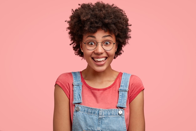 Headshot di felice donna afroamericana indossa maglietta e salopette di jeans