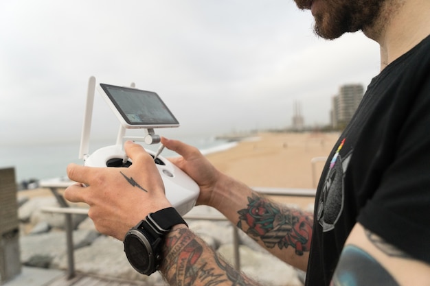 Hipster tecnologicamente esperto o fotografo professionista millenario di giovane generazione utilizza il telecomando per pilotare droni o gadget quadricotteri in aria