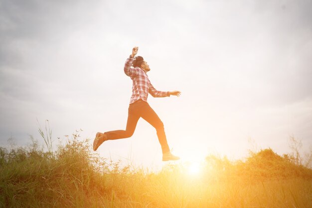 Hipster uomo salto in alto, libertà godendo con la natura aroun