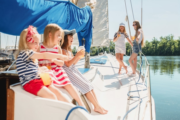 I bambini a bordo dello yacht del mare bevono succo d'arancia