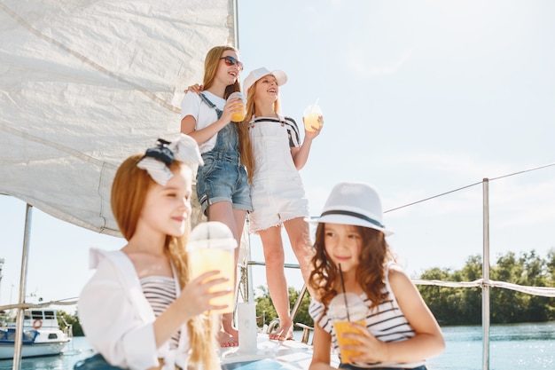 I bambini a bordo dello yacht del mare bevono succo d'arancia