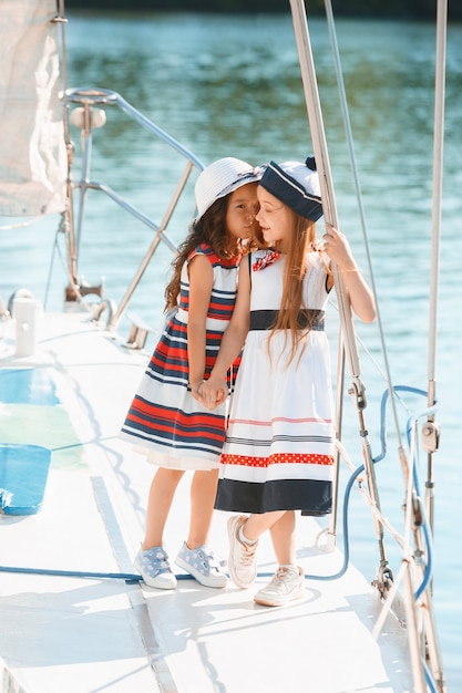 I bambini a bordo di uno yacht da mare. Le ragazze adolescenti o bambine all'aperto. Vestiti colorati. Concetti di moda per bambini, estate soleggiata, fiume e vacanze.