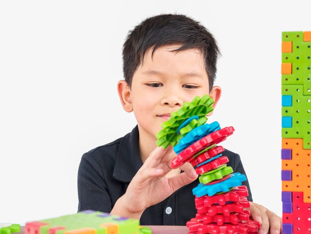 I bambini asiatici stanno giocando il gioco creativo del blocco di plastica del puzzle