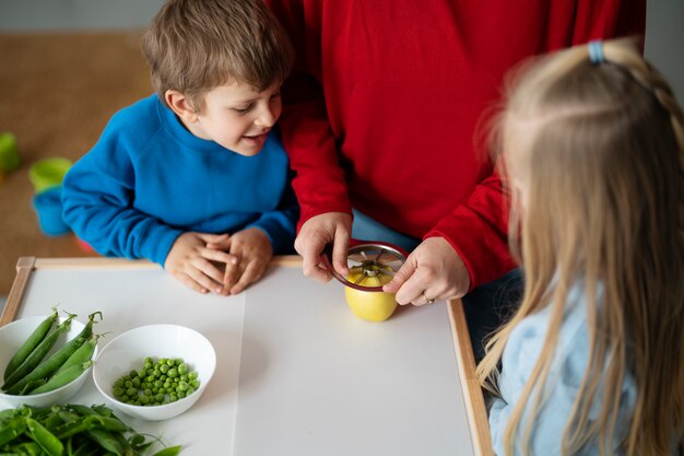 I bambini dell'angolo alto che guardano l'insegnante tagliano la mela