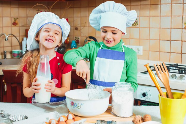 I bambini divertenti della famiglia felice stanno preparando la pasta, cuociono i biscotti in cucina