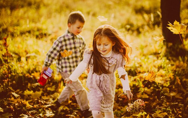 I bambini giocano con foglie cadute in serata