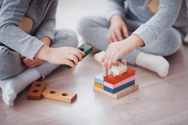I bambini giocano con un designer di giocattoli sul pavimento della stanza dei bambini. Due bambini che giocano con blocchi colorati. Giochi educativi per la scuola materna