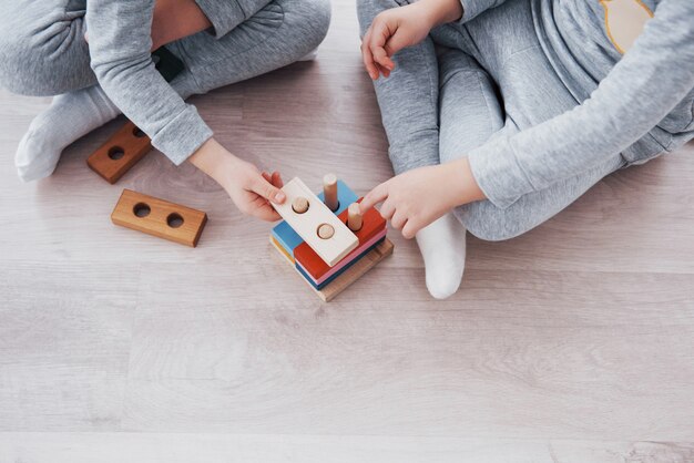 I bambini giocano con un designer di giocattoli sul pavimento della stanza dei bambini. Due bambini che giocano con blocchi colorati. Giochi educativi per la scuola materna