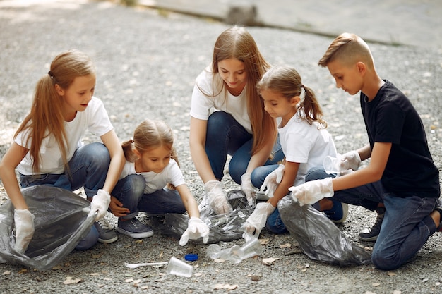 I bambini raccolgono immondizia nei sacchetti di immondizia nel parco