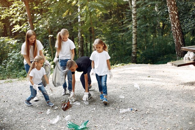 I bambini raccolgono immondizia nei sacchetti di immondizia nel parco