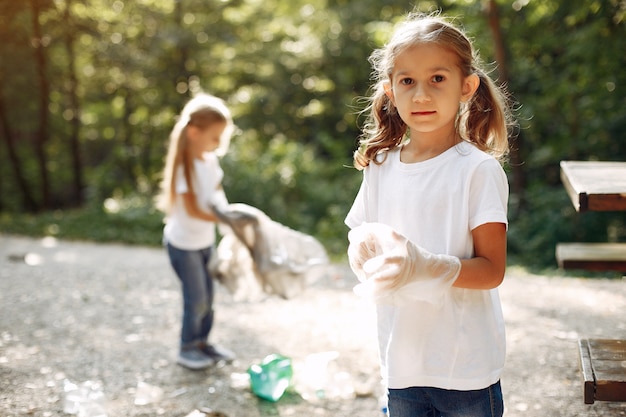 I bambini raccolgono immondizia nei sacchetti di immondizia nel parco