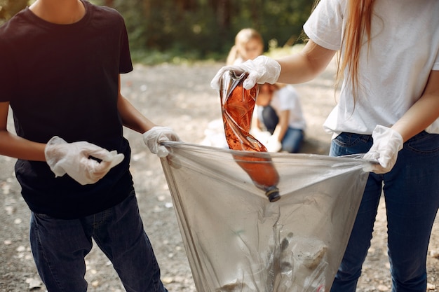 I bambini raccolgono immondizia nei sacchetti di immondizia nel parco