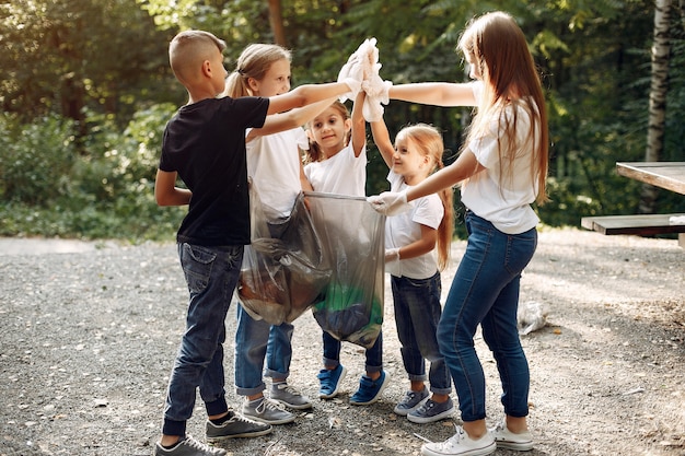I bambini raccolgono immondizia nei sacchetti di immondizia nel parco
