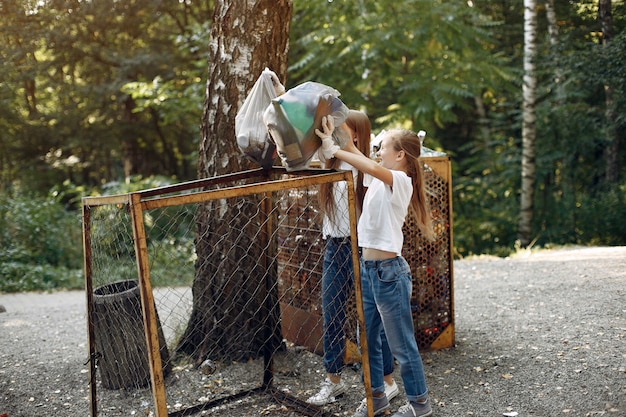 I bambini raccolgono immondizia nei sacchetti di immondizia nel parco