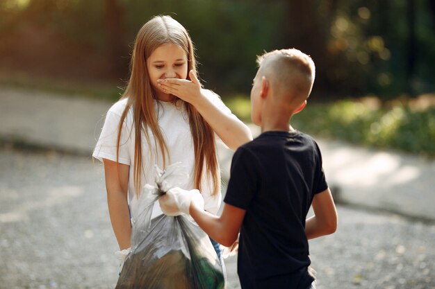 I bambini raccolgono immondizia nei sacchetti di immondizia nel parco