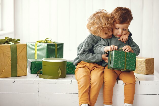 I bambini si avvicinano all'albero di Natale in un maglione grigio