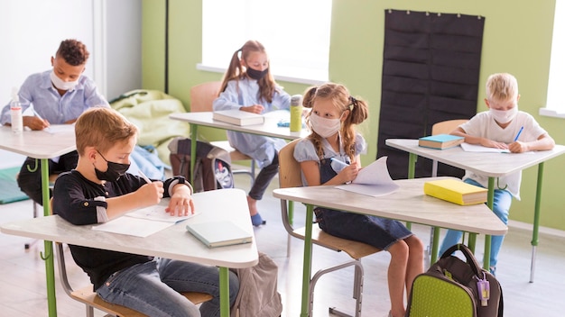 I bambini si proteggono con maschere facciali in classe