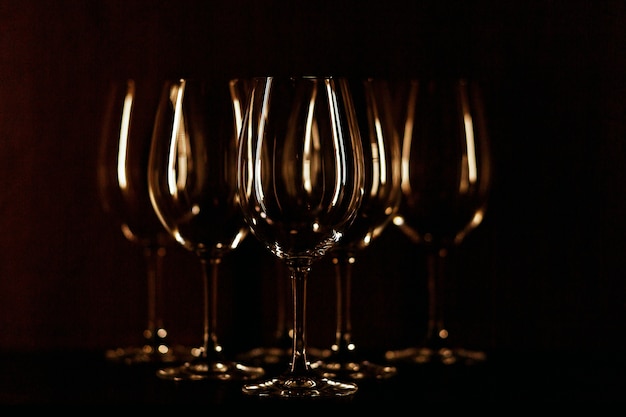 I bicchieri da vino illuminati con luce calda stanno su sfondo nero
