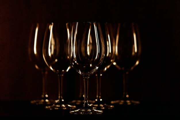 I bicchieri da vino illuminati con luce calda stanno su sfondo nero