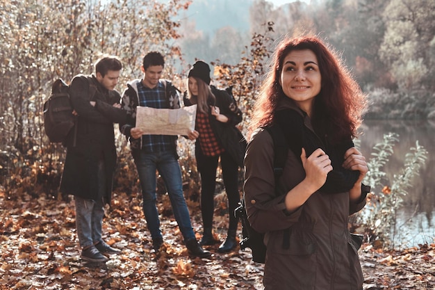 I buoni amici si divertono nella foresta autunnale, usano una mappa per trovare il posto migliore per passeggiare.