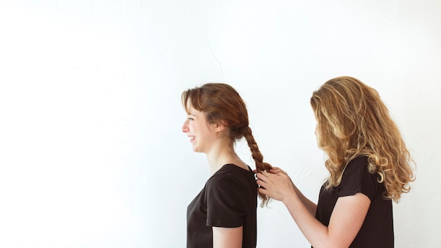 I capelli della sorella intrecciante della donna isolati sopra fondo bianco