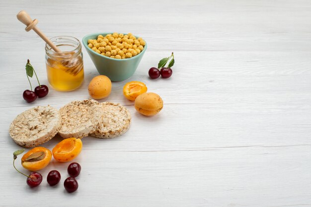 I cereali crudi di vista frontale dentro il piatto con i cracker fruttifica e miele su bianco, beve la prima colazione della latteria della latteria del latte della bevanda