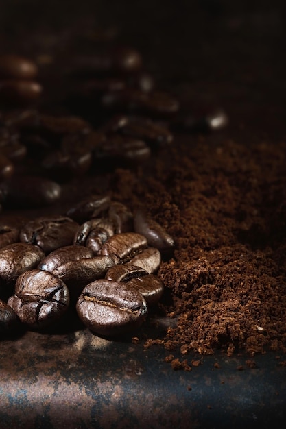 I chicchi di caffè appena tostati fragranti e il caffè macinato sono sparsi su un vassoio di metallo Cornice verticale con messa a fuoco selettiva del primo piano