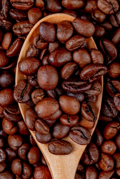 I chicchi di caffè in un cucchiaio di legno sui chicchi di caffè si chiudono sulla vista