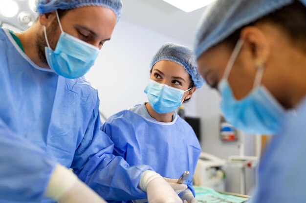 I chirurghi in una sala operatoria leggera eseguono la chirurgia plastica, un team di medici maschi e femmine esegue la chirurgia ricostruttiva