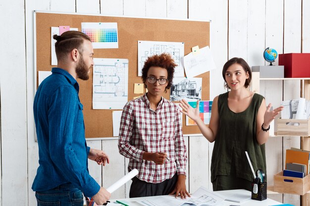 I colleghi sorridono, parlano, discutono di disegni, nuove idee in ufficio