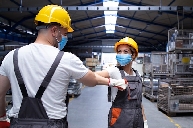 I dipendenti della fabbrica si salutano con un colpo di gomito a causa della pandemia globale del coronavirus e del pericolo di infezione