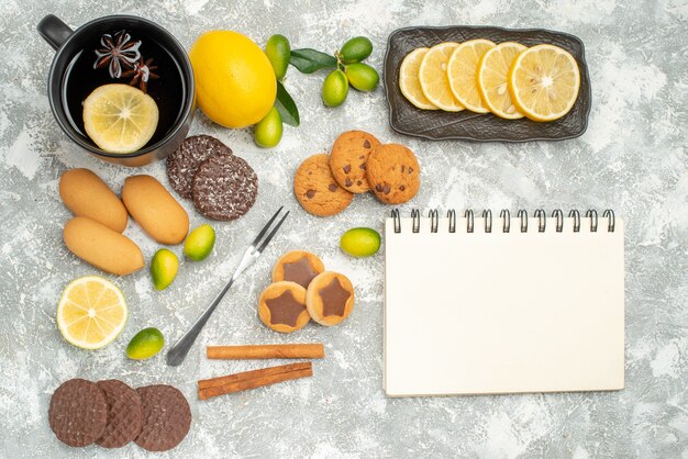 I dolci di vista ravvicinata dall'alto forchetta i biscotti appetitosi una tazza di taccuino degli agrumi del tè