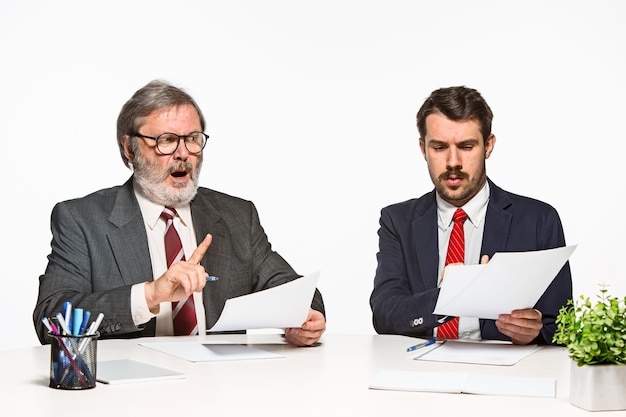 I due colleghi che lavorano insieme in ufficio su sfondo bianco. Discutono attivamente ed emotivamente i piani attuali