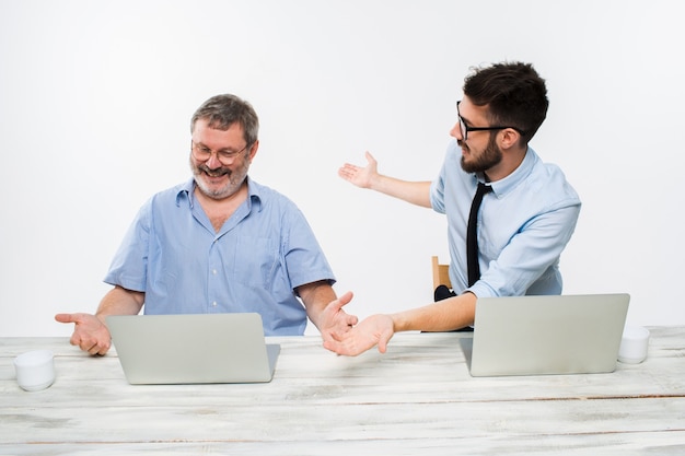 I due colleghi che lavorano insieme in ufficio su sfondo bianco. entrambi gli uomini felici stanno ricevendo buone notizie. concetto di successo negli affari.