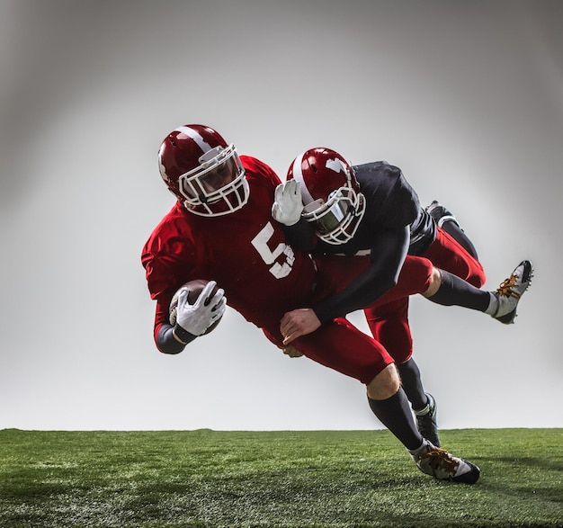 I due giocatori di football americano in azione su erba verde e grigia