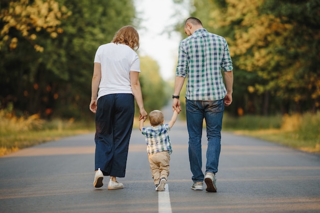 I genitori che tengono il loro piccolo figlio stanno camminando su una strada