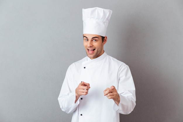 I giovani allegri cucinano in uniforme che indica voi.