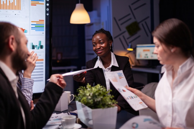 I maniaci del lavoro si sono concentrati su uomini d'affari multietnici che lavoravano troppo nella sala riunioni dell'ufficio aziendale per idee di brainstorming a tarda notte