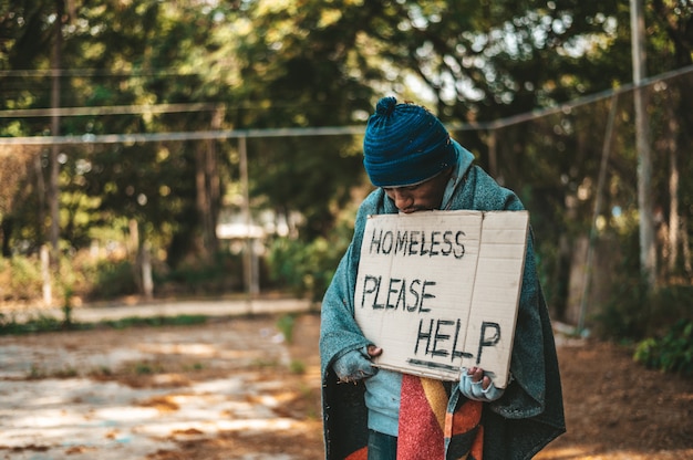 I mendicanti stanno in strada con messaggi di senzatetto per favore aiutatemi.