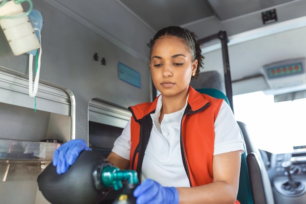 I paramedici di sesso femminile forniscono assistenza medica a un paziente ferito sulla strada per un assistente sanitario di emergenza dell'ospedale che indossa una maschera di ventilazione non invasiva in un'ambulanza