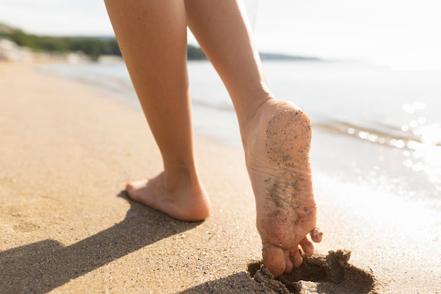 I piedi della donna sulla spiaggia di sabbia