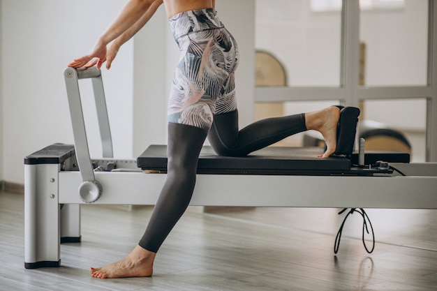 I pilates di pratica della donna in un riformatore dei pilates si chiudono su