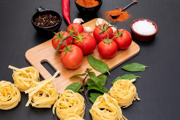 I pomodori con le spezie di concetto della pasta salano sul tagliere di legno